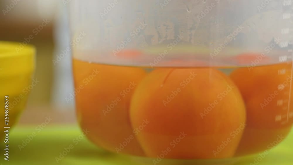 A man or woman puts red tomatoes in a plastic bowl and pour boiling water over it. A man or woman puts red tomatoes in a plastic bowl and pour boiling water over it.