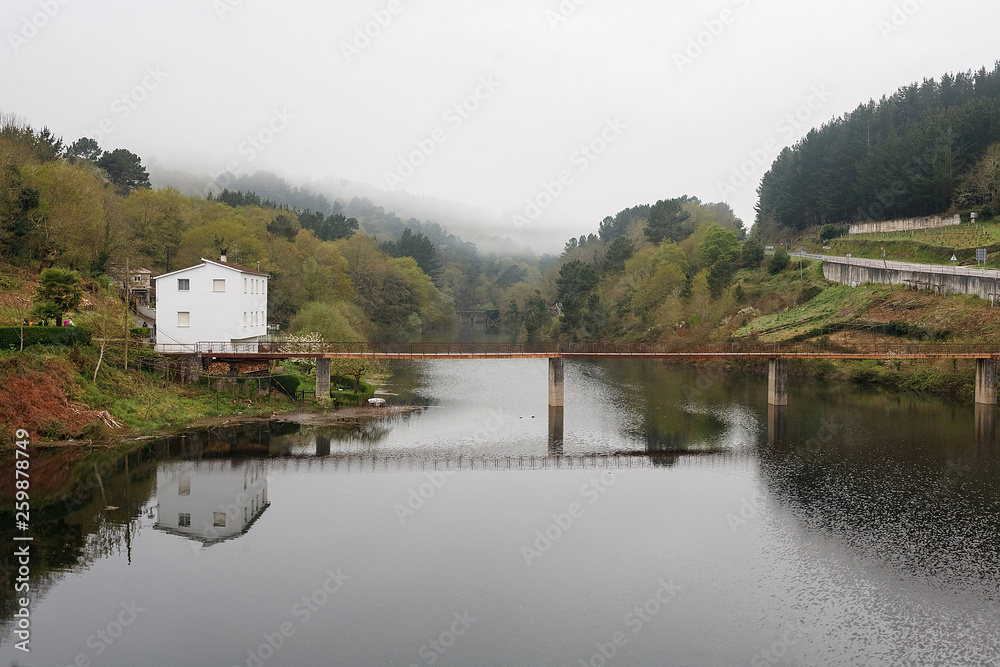 Fototapeta premium Bridge over the Minho River in Portomarin, Spain under the fog