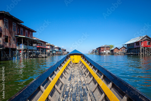 Traditional Bamboo boat is heading to famous Inle Lake floating village with wooden houses