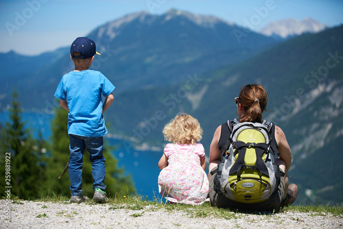 Frau mit Rucksack steht auf einem Berg und blickt mit ihren zwei Kindern über den Achensee in Tirol
