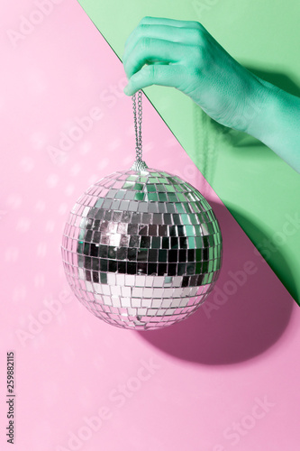 Shiny disco ball on a bright pastel creative background. Pop disco music style attributes eighties