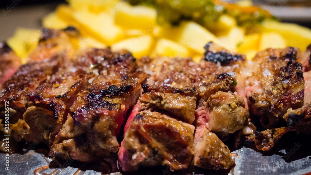 Close-up detail of a beef rib grilled with fried potatoes