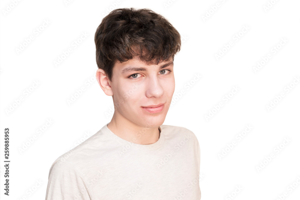 Portrait of a handsome teenage boy on a white background. The guy is standing sideways and smiling Portrait of a handsome teenage boy on a white background. The guy is standing sideways and smiling