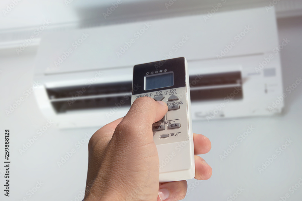 close-up of male hand with air conditioner remote control close-up of male hand with air conditioner remote control