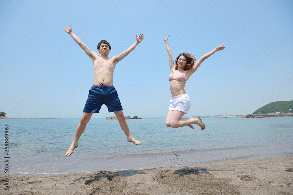 ビーチでジャンプするカップル