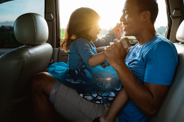 daddy tickling her little girl in the car