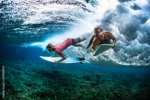 Photography Two young surfers man and woman survive under the breaking ocean wave