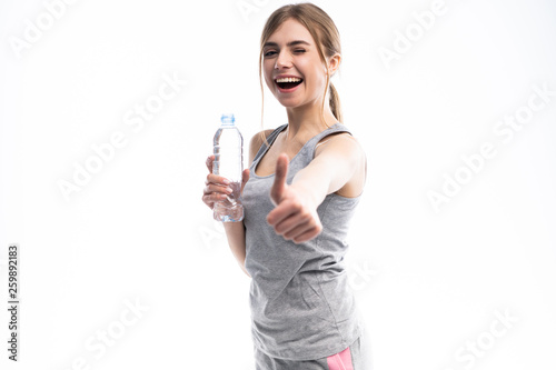 Sport girl with water and show thumb up isolated on white background