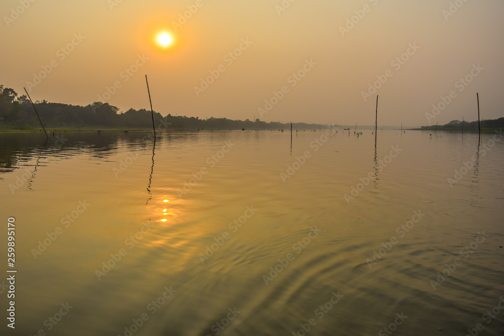 A stunning, natural dramatic, blazing sunset with reflection on over holiest of rivers in India Ganges delta in Sunderbans, West Bengal, India.
