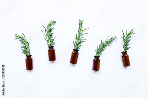 Bottle of essential oil with rosemary on white