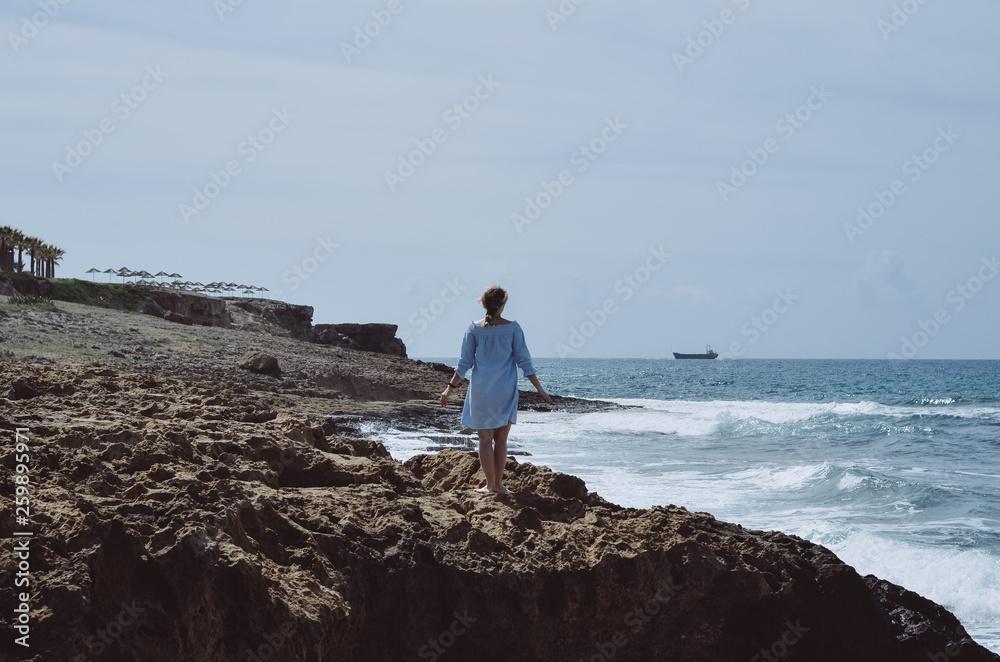 Girl in blue dress near sea. Wanderlust travel concept. Sea vacation concept. Freedom and travel concept. Mediterranean Sea