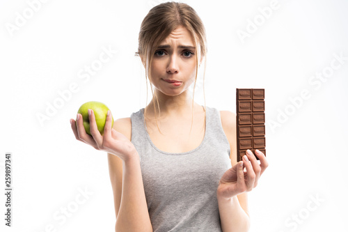 Diet. Dieting concept. Healthy Food. Beautiful Young Woman choosing between Healthy and Unhealthy Food.Fruits or Sweets. Isolated on a White