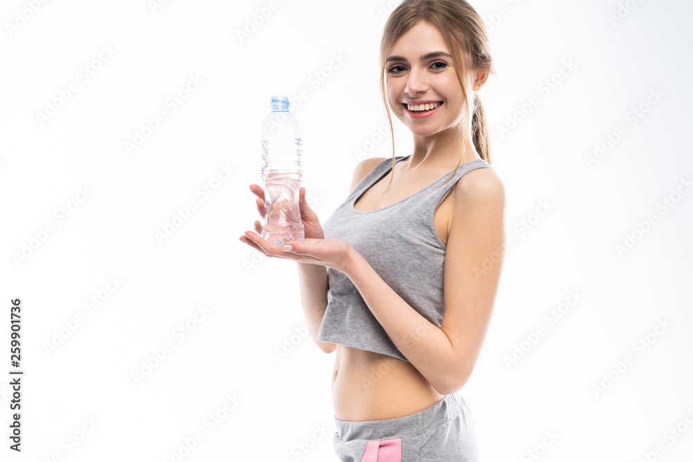 Female fitness model holding a water bottle in a white studio environment. Female fitness model holding a water bottle in a white studio environment.