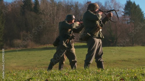 WWII - German soldiers walk over meadow weapons in ready photo
