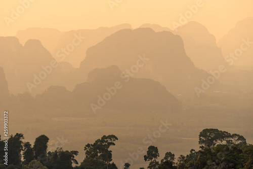 Landscape view of silhouettes and shapes of hazy mountains and hills in asia in orange sunset time