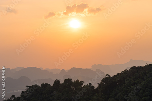 Fototapeta Naklejka Na Ścianę i Meble -  Beautiful orange sunset in Asian jungle with misty outlines of mountains in the distance