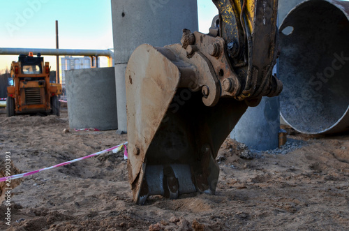 Iron excavator bucket in the sandy ground, earthworks concept