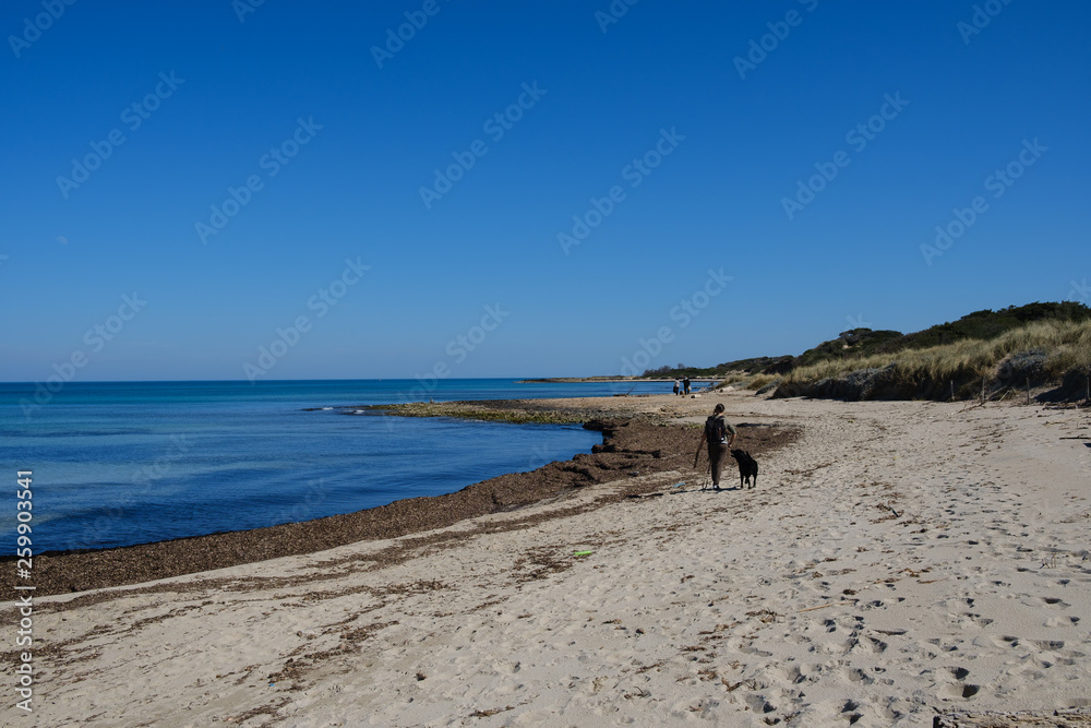Frau mit Hund macht Spaziergang am Strand am Mittelmeer Frau mit Hund macht Spaziergang am Strand am Mittelmeer