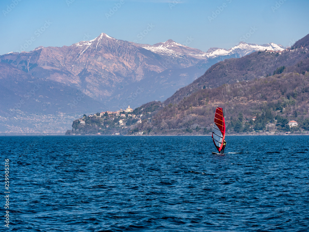 Image of surfer on the lake maggiore with city and alps with snow peaks in the background
