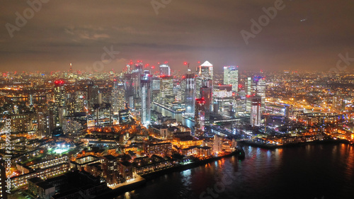 Aerial drone night shot from iconic Canary Wharf illuminated skyscrapers business and financial area  Docklands  Isle of Dogs  London  United Kingdom