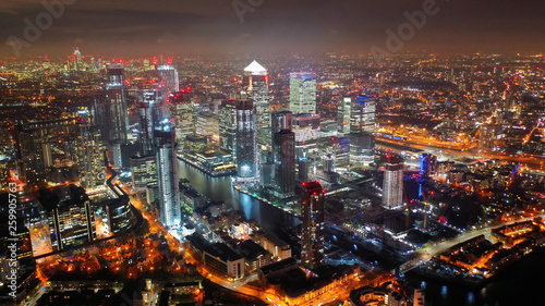 Aerial drone night shot from iconic Canary Wharf illuminated skyscrapers business and financial area, Docklands, Isle of Dogs, London, United Kingdom