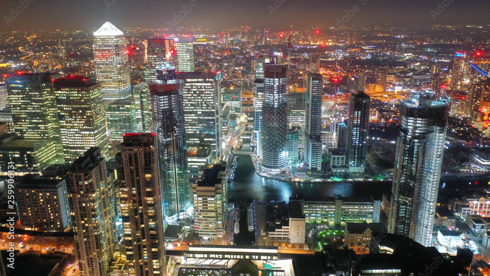 Aerial drone night shot from iconic Canary Wharf illuminated skyscrapers business and financial area, Docklands, Isle of Dogs, London, United Kingdom
