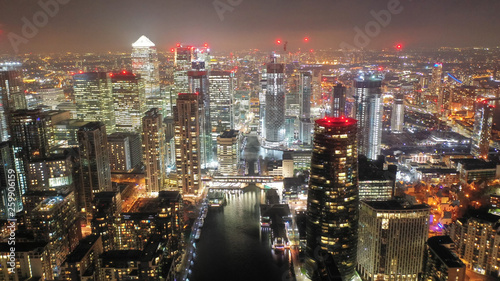 Aerial drone night shot from iconic Canary Wharf illuminated skyscrapers business and financial area  Docklands  Isle of Dogs  London  United Kingdom