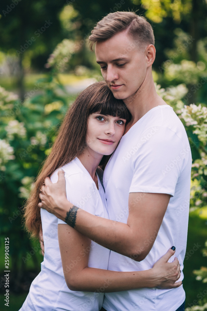 Meeting lovers in the park. The guy and the girl retired in flowers.