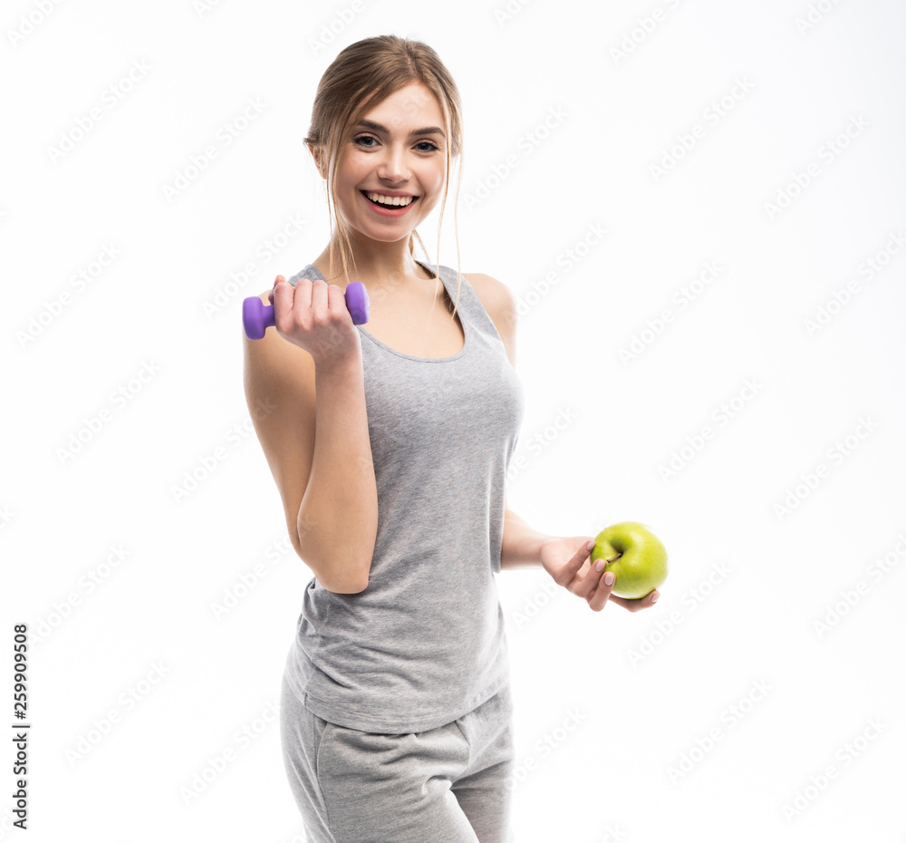 Sporty fit woman holding dumbbells weights in one and apple fruit in another hand. Fitness and healthy dieting concept.