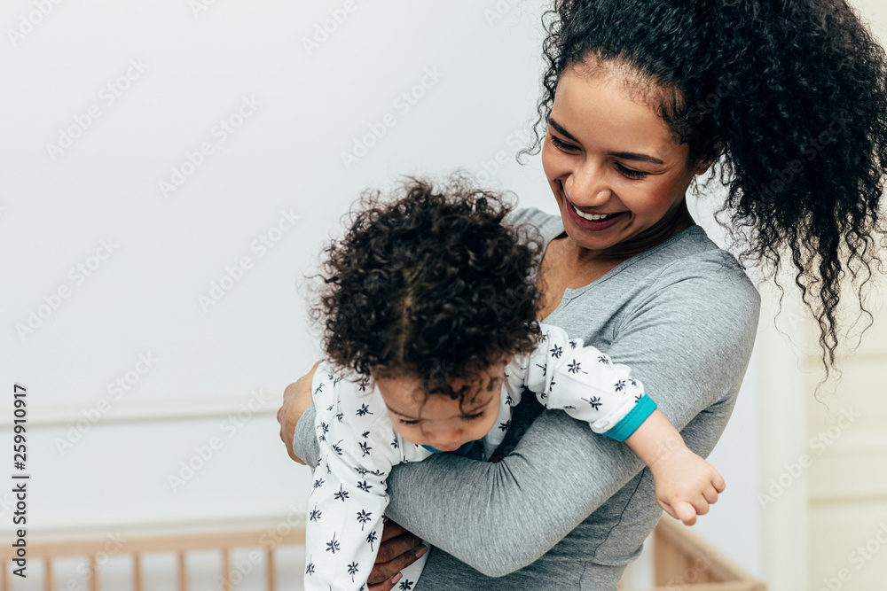 Happy mother swinging her little son in living room Happy mother swinging her little son in living room