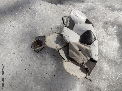 torn ball for playing soccer lying on the snow