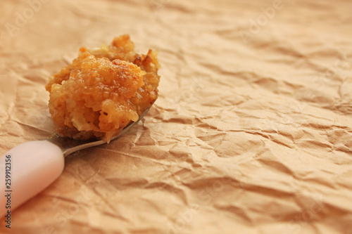 Raw honeycomb cappings in a spoon on a paper background photo