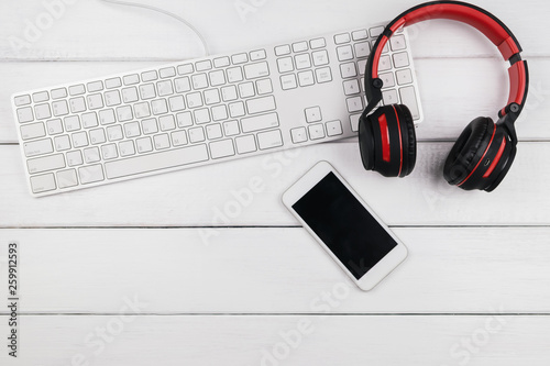 Headphone mobile phone and keyboard on wood background