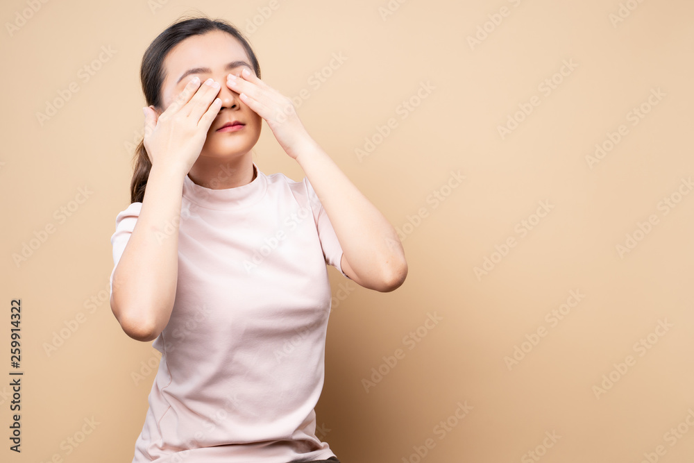 Woman has eyes pain isolated over beige brown background Woman has eyes pain isolated over beige brown background