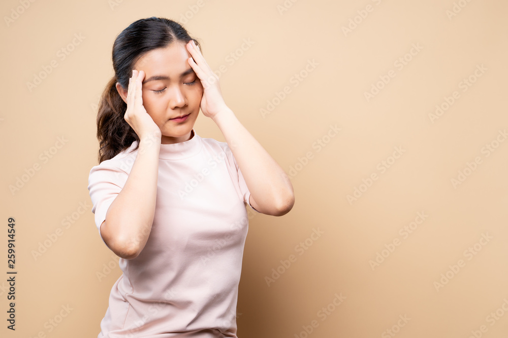 Woman has headache isolated over beige brown background Woman has headache isolated over beige brown background