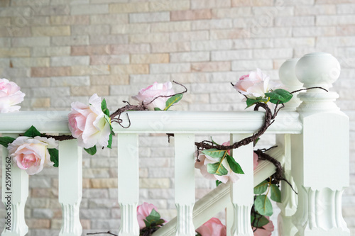 close-up of railing staircase covered with artificial rose and ivy.