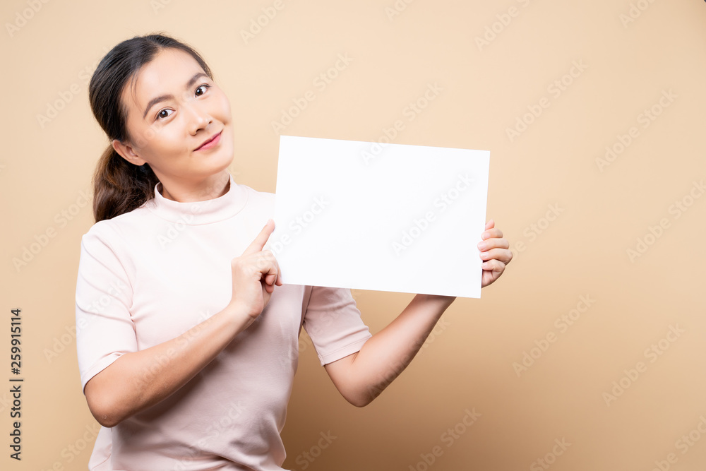 Woman showing paper copy space isolated over beige brown background Woman showing paper copy space isolated over beige brown background