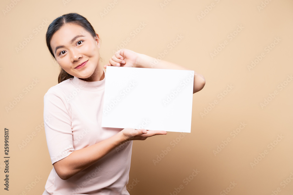 Woman showing paper copy space isolated over beige brown background Woman showing paper copy space isolated over beige brown background