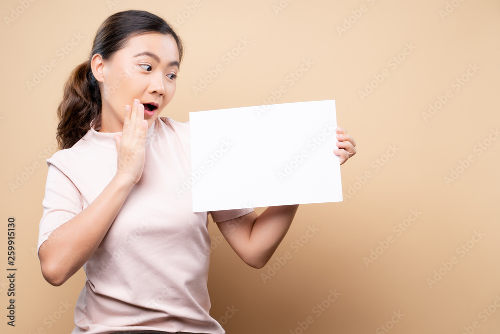 Woman showing paper copy space isolated over beige brown background Woman showing paper copy space isolated over beige brown background
