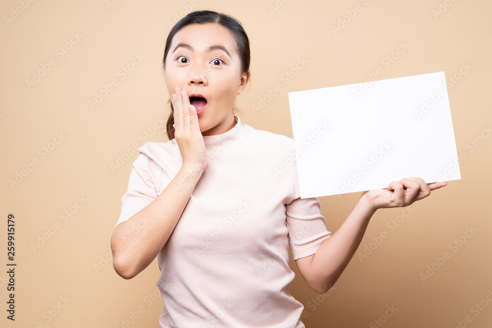 Woman showing paper copy space isolated over beige brown background Woman showing paper copy space isolated over beige brown background