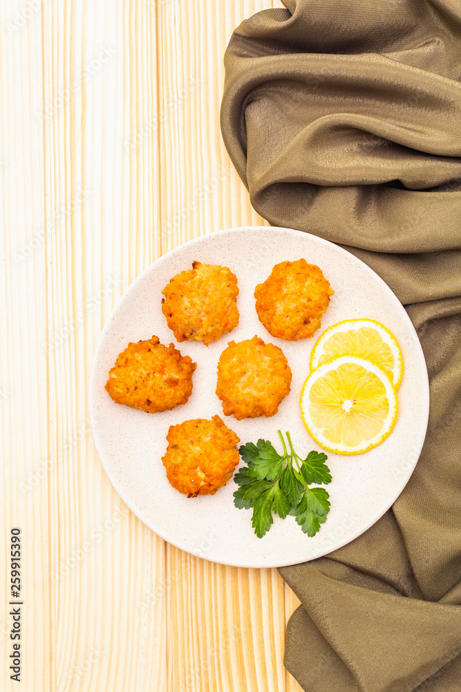 Homemade red fish cakes with lemon and parsley in ceramic plate. With fabric drapery on wooden background, top view. Homemade red fish cakes with lemon and parsley in ceramic plate. With fabric drapery on wooden background, top view.