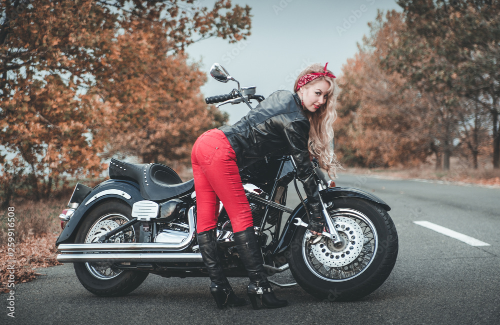 Young beautiful caucasian woman posing with motorcycle on the road.