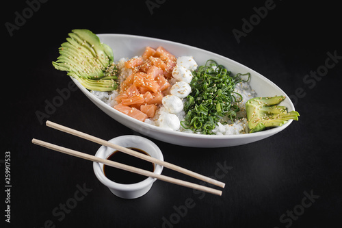 Fotografie Nikkey gohan with white rice, salmon, avocado and philadelphia cheese on a black
