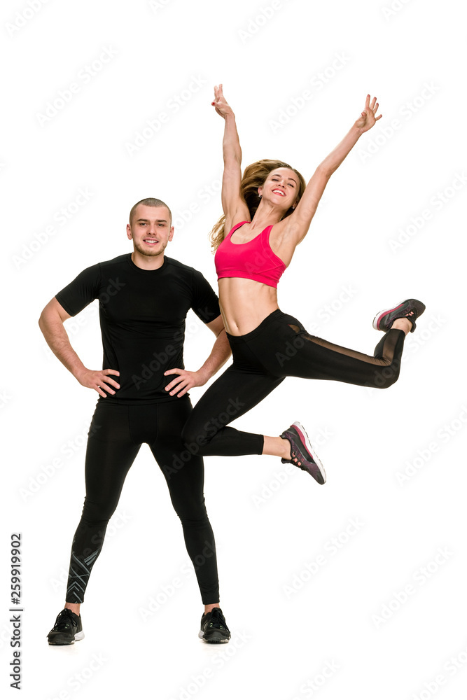 Obraz premium Athletic man posing while his slim girlfriend jumping on white background