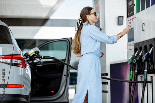 Fototapeta Woman paying with phone for gasoline, photographing bar code on the gas station