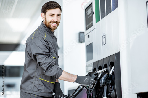 Gas station worker in uniform taking filling gun, refueling car at the gas station photo