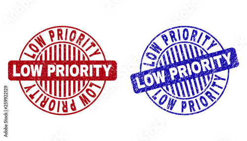 Grunge LOW PRIORITY round stamp seals isolated on a white background. Round seals with distress texture in red and blue colors.