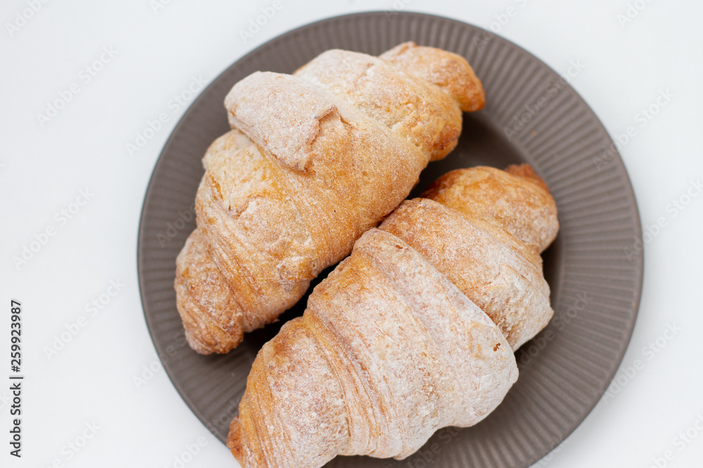 breakfast croissants sprinkled with powdered sugar on a gray plate. white background breakfast croissants sprinkled with powdered sugar on a gray plate. white background