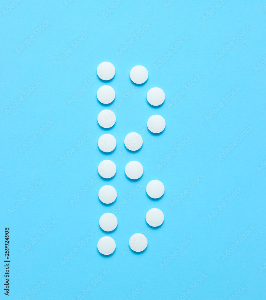 Vitamin B. Letter B from white pills on blue background. Minimalistic medical concept. Top view. Vitamin B. Letter B from white pills on blue background. Minimalistic medical concept. Top view.