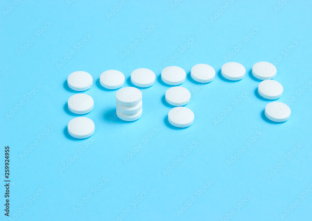 Vitamin E. Letter E from white pills on blue background. Minimalistic medical concept.